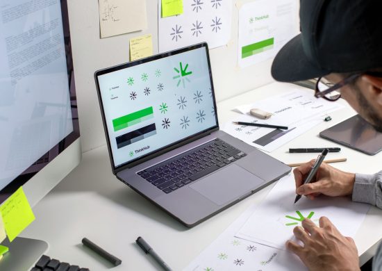 Asian graphic designer making notes on logo designs, using computers, designing logos, and showcasing the corporate identity and logo design process.